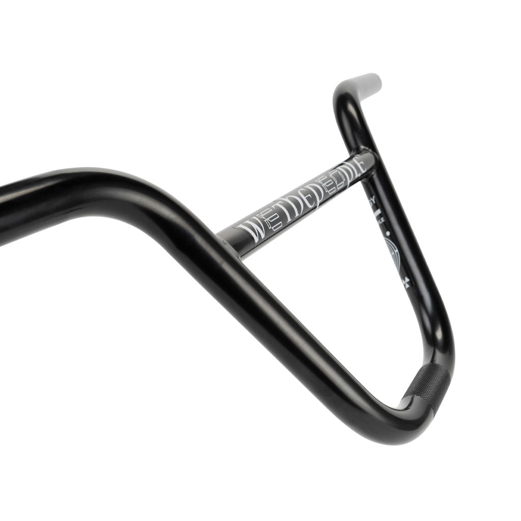 Close-up view of a black Wethepeople Prodigy Handlebar with white markings and text, featuring ergonomic grips and a raised middle section, highlighting its lightweight construction.