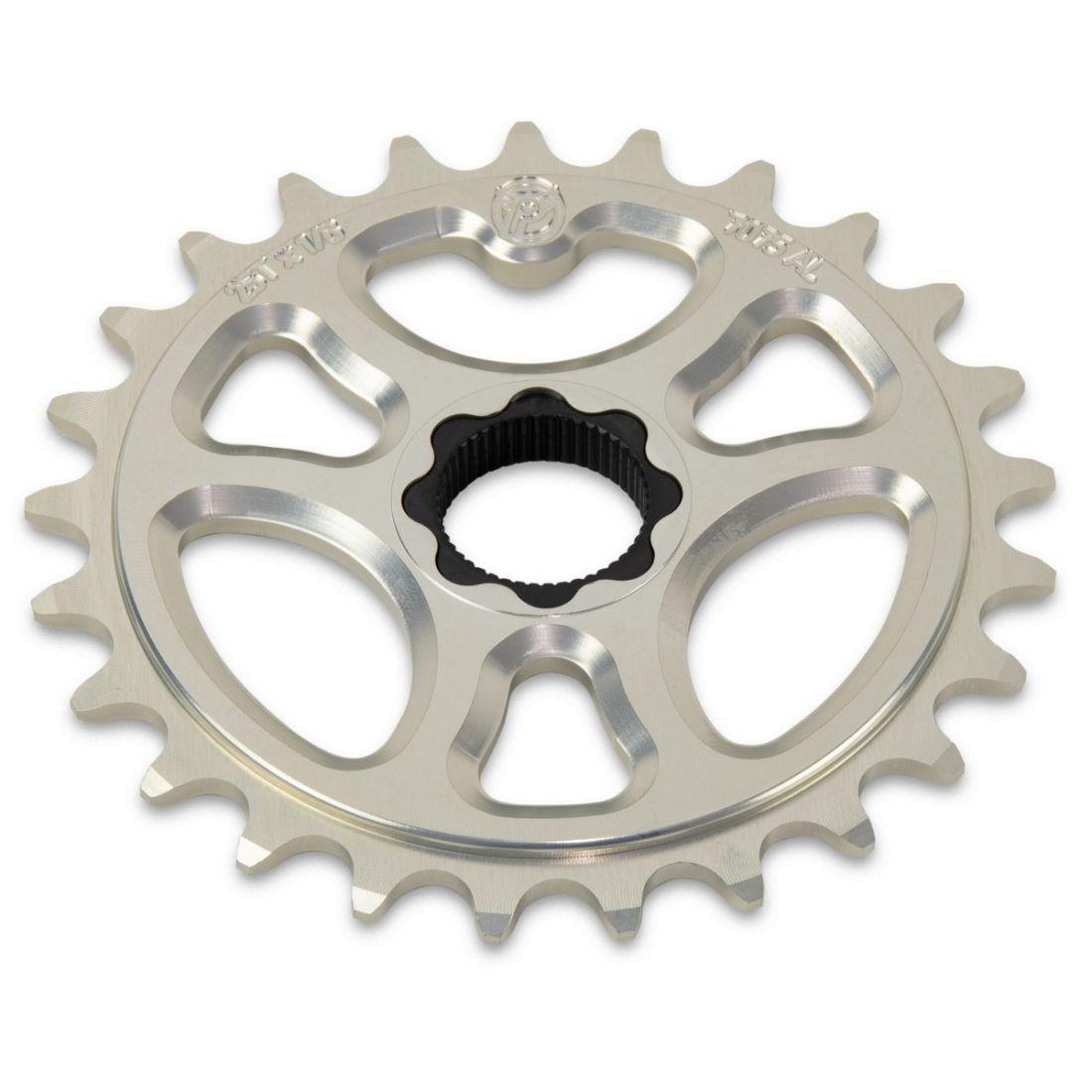 The Profile Galaxy Spline Drive Sprocket is a silver metal bicycle sprocket with 26 teeth, made from durable 7075 Aluminum. It has a central mounting hole and includes a CrMo steel insert for enhanced strength and longevity.