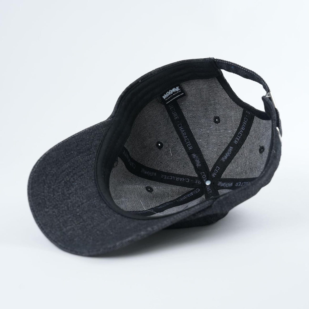 The Backbone Real Deal 6 Panel Hat in dark gray is upside down, showcasing its inner lining details and the black adjustable strap at the back.