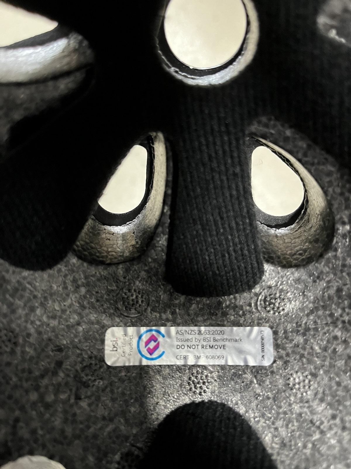 Interior of the S-One Lifer Helmet / Black Matte/Cyan Straps showing a compliance sticker with AS/NZS 4330:2020 certification issued by BSI Benchmark.