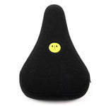 A black bicycle seat cover with a small yellow smiley face emblem at the center features a custom-molded patch by designer Jordan Capece of Stranger JCAP Pivotal.