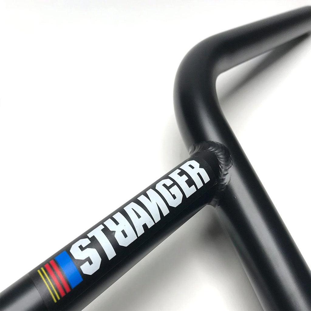 Close-up of a black Chromoly bicycle handlebar with the word "STRANGER" and a colored stripe design, reminiscent of the iconic Stranger NAS bars.