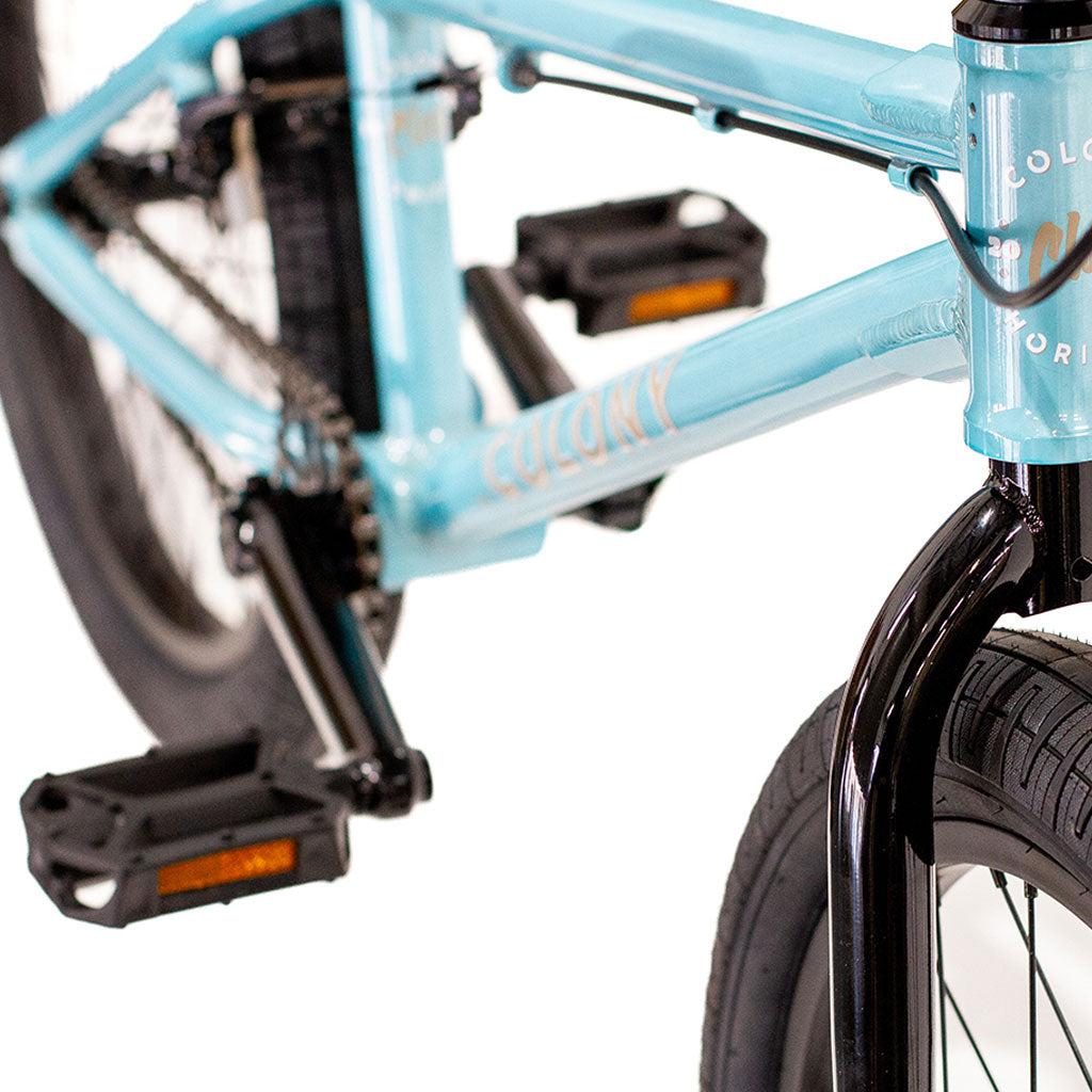 Close-up view of a light blue Colony Horizon 12 Inch Bike featuring black pedals and tires. The brand name "Colony" is prominently displayed on the lightweight alloy frame.