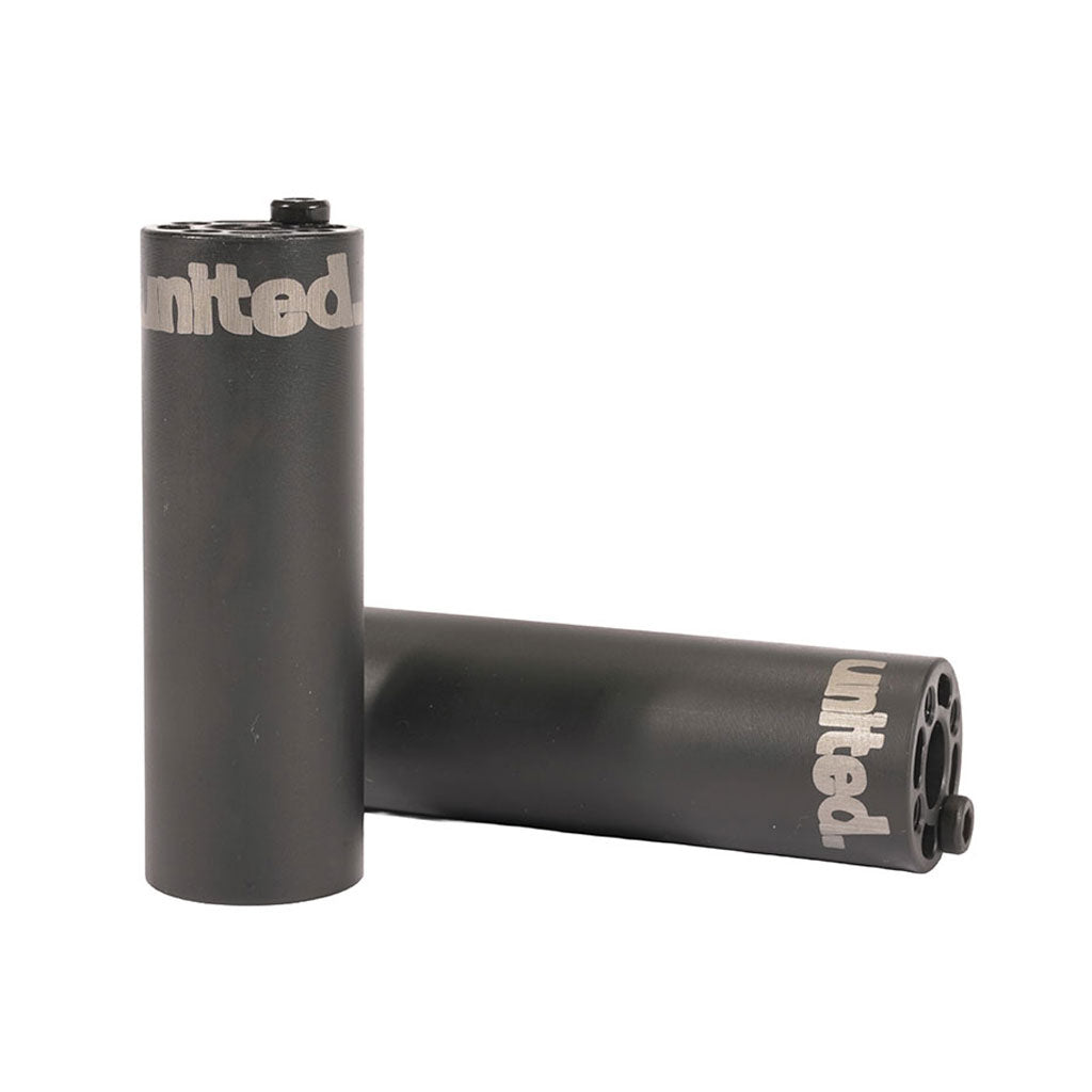 Two black United RDS Pegs, featuring a silver "united" logo and made from heat-treated 4140 Cromo, are shown upright and lying down against a white background.