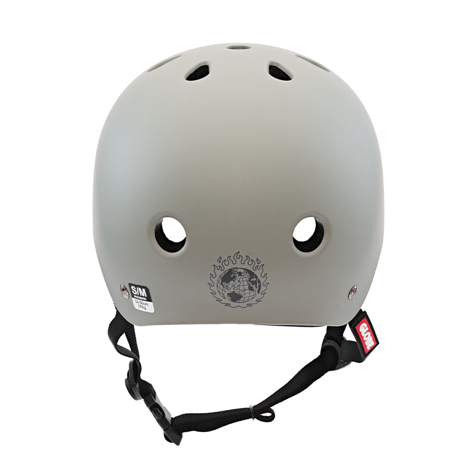 A grey skate helmet with a flame and skull design on the front, ventilation holes on top, and adjustable black straps with a clip. This Goodstock Certified Helmet / Matte Gunmetal/Bandana offers high and low impact protection and features CoolMax liner tech for comfort.