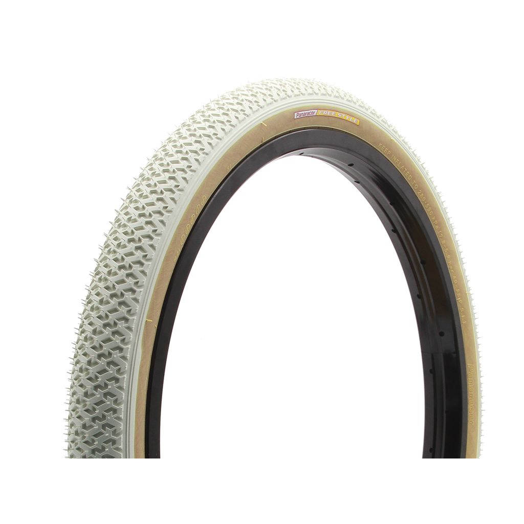 Close-up of a bicycle tire with a light-colored original tread, mounted on a black rim. The Panaracer Freestyle HP Tyre's pattern features a series of small raised triangular shapes for grip, and it supports up to 85 PSI for optimal performance.